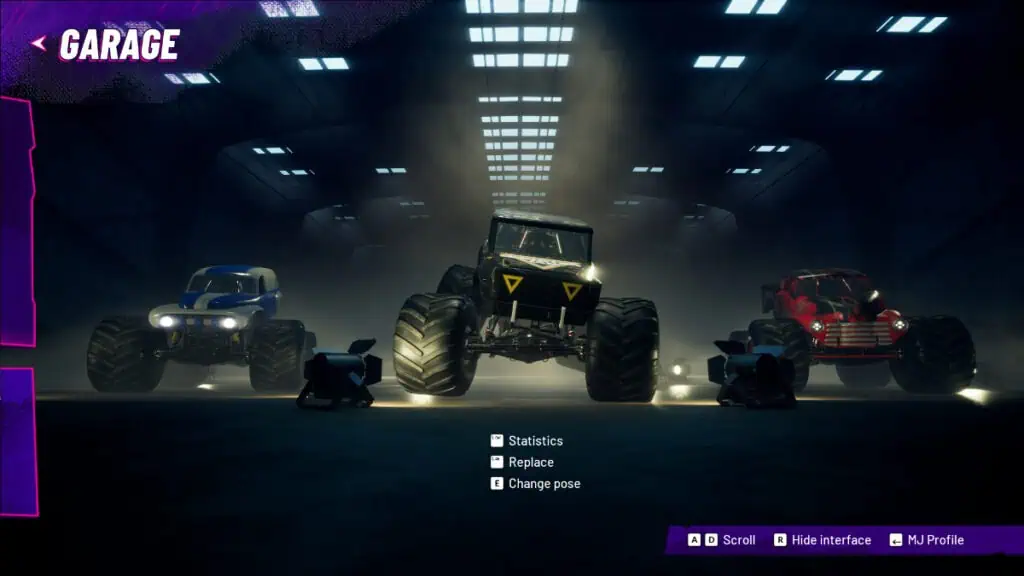 Several monster trucks sit in a garage