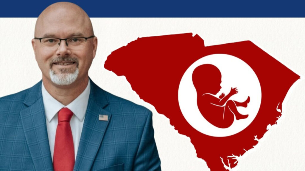 South Carolina Bill To Execute Women Who Seek Abortion Advances Under Trump Admin: ‘We’re Killing Women Now?’ South Carolina State Rep. Rob Harris poses beside a picture of the state with a stylized baby inside