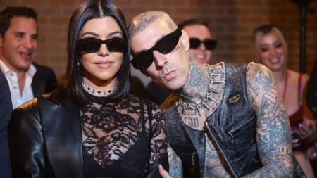 Kourtney Kardashian and Travis Barker pose at fashion show event.