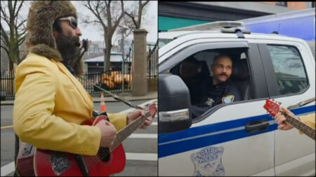 Musical comedian Robby Roadsteamer wears a yellow coat and plays guitar while singing to Boston cops