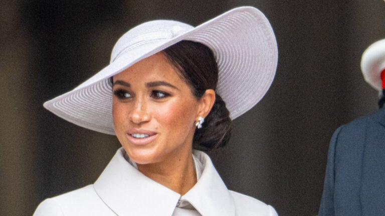 Meghan Markle stands with husband Prince Harry in white outfit.