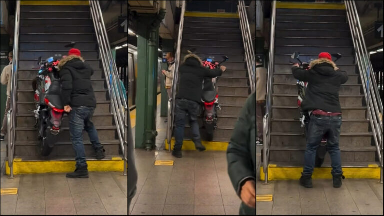A rider awkward tries to force their motorcycle up the subway stairs in NYC