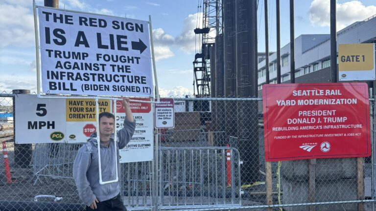 Human Sign Fact Checks Trump in Seattle: ‘The Red Sign Is a Lie’ A Seattle man dons a large sign fact checking a nearby sign's claims about Trump